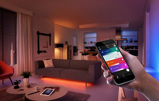 Suosituimmat älyvalot ovat HomeKit-yhteensopivia Käsi pitelee älypuhelinta värikkäästi valaistussa olohuoneessa