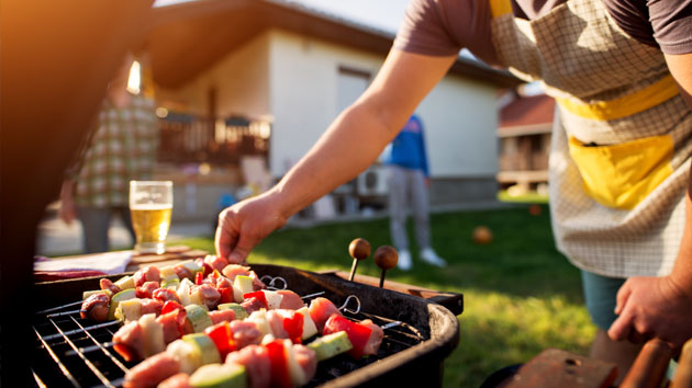 Grillausvinkit Mies seisoo pihalla grillaamassa erilaisia vartaita