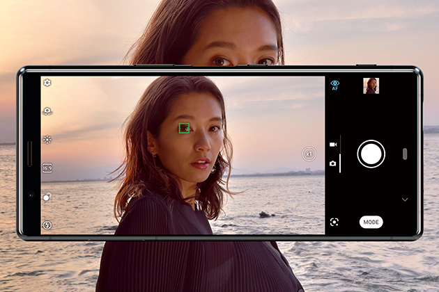 Sony Xperia 5:ssa on edistynyt kolmen linssin kamera Nainen Sony Xperia 5 -puhelimen kameran edessä