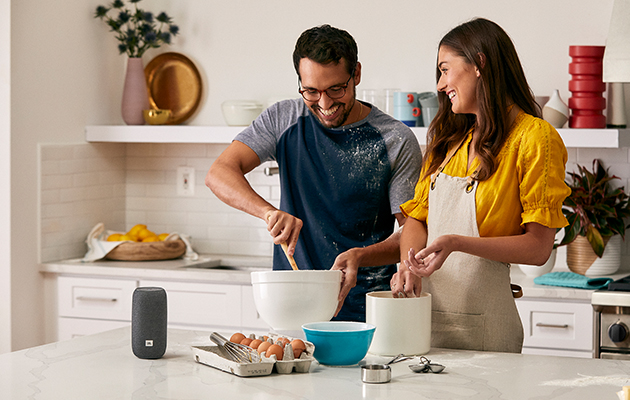 JBL Link toistaa musiikkia joko WiFin tai Bluetoothin välityksellä JBL Link -kaiutin keittiössä, jossa pariskunta laittaa ruokaa