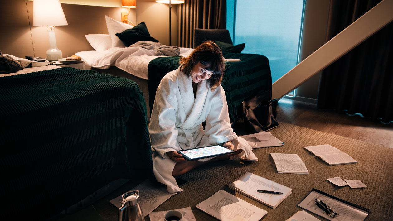 Microsoft Surface Pro 7 on tehokas työkone kaikissa tilanteissa Nainen istuu hotellihuoneen lattialla ja työskentelee Surface Pro 7 -laitteella.
