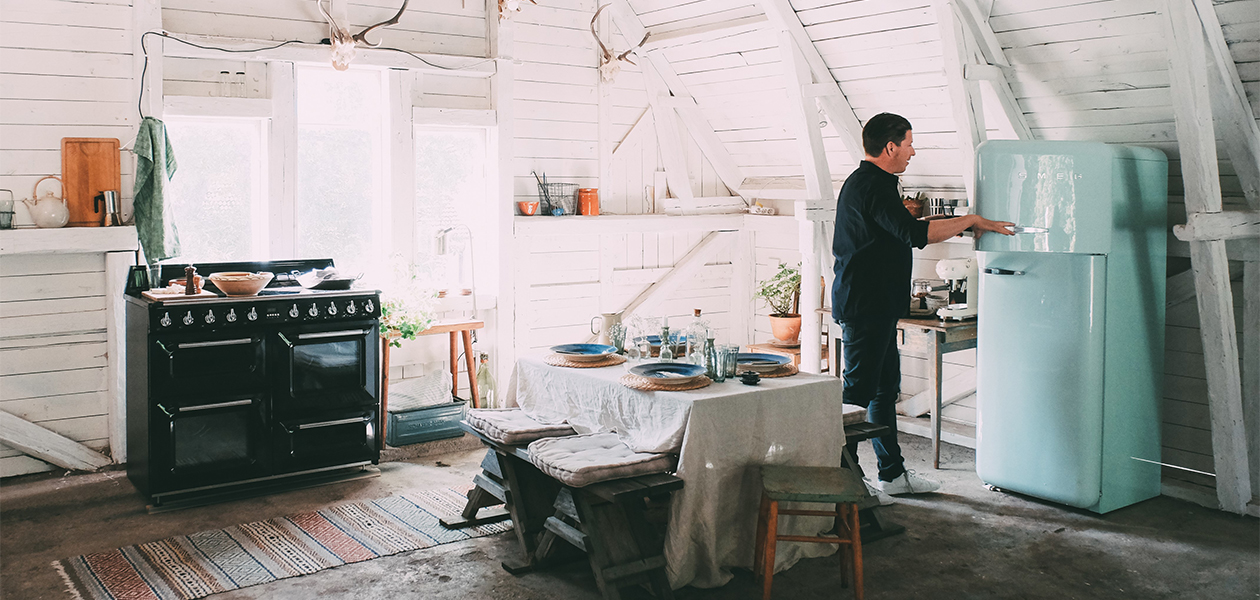 Smeg - muotoilua Italiasta Mies avaamassa vaaleansinisen Smeg-jääkaapin ovea keittiössään