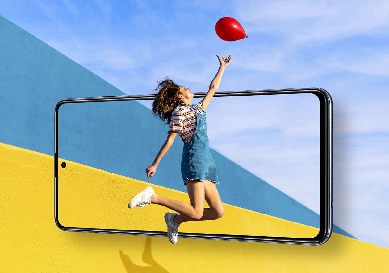Käytännöllinen ja elegantti Suurennettu kuva Samsung Galaxy A51 -puhelimesta, jonka edessä tyttö hyppää ottamaan punaisen ilmapallon kiinni