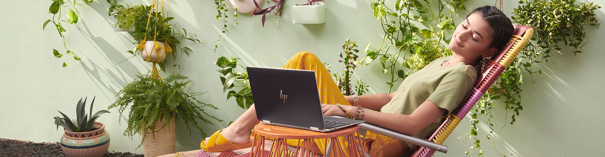 Hurmaava HP Spectre x360 Nainen rentoutuu aurinkotuolissa HP Spectre x360 -kannettava vierellään