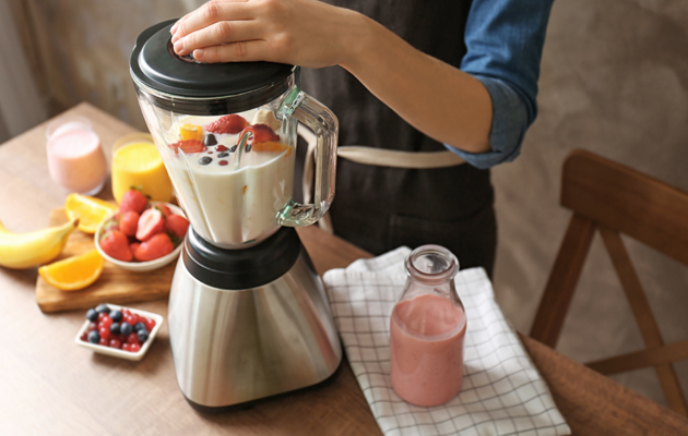 Nainen valmistaa smoothieta tehosekoittimella