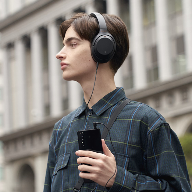 Korkealaatuinen ääni Mies, jolla Sony-kuulokkeet korvilla ja Sony Xperia 1 II -puhelin kädessä