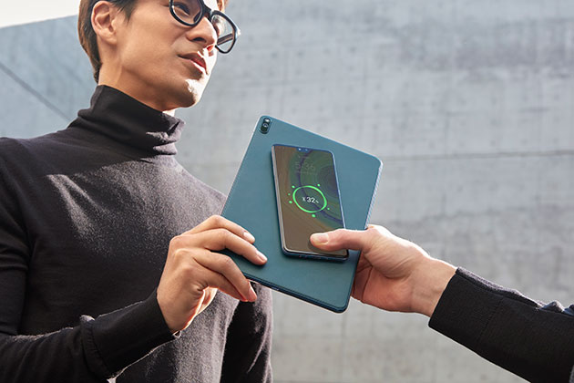Pitkäkestoinen akku Mies pitää Huawei MatePad Pro -tablettia, samalla ladaten toisen henkilön puhelinta