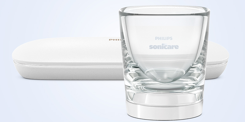 Tarvikkeet Philips Sonicare -logolla varustettu juomalasia muistuttava laturi ja valkoinen matkakotelo