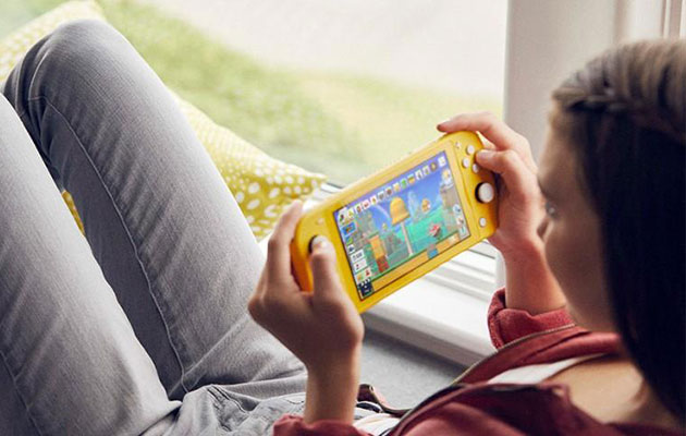 Nintendo Switch Lite on kompakti pelikonsoli Nuori nainen istuu ikkunan vieressä pelaamassa Nintendo Switch Lite -konsolilla