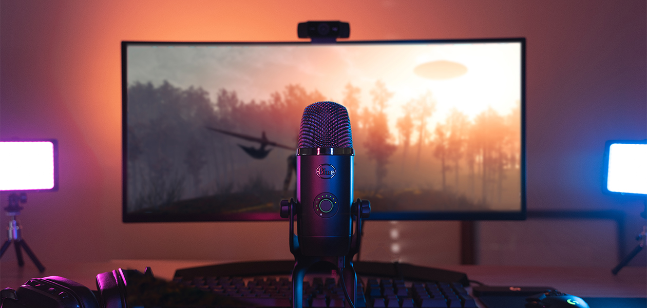 Laadukkaammat striimit Blue Yeti -mikrofoni pöydällä näytön ja Logitech C922 -webkameran edessä.