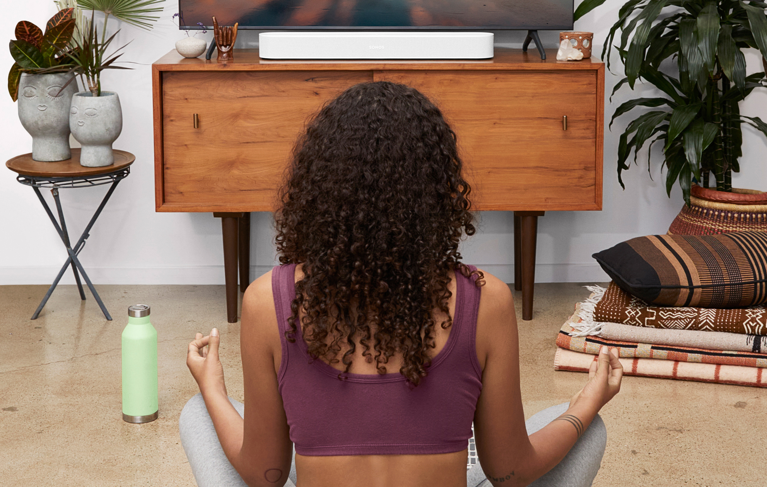 Sonos Beam (Gen 2) ja lotus-asennossa oleva nainen