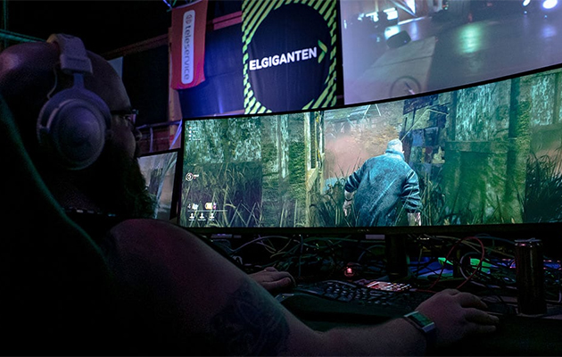 Gaming Weekend - LAN-Party Mies istuu pelaamassa kaarevan pelinäytön ääressä