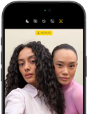 iPhone 18 Pro, musta, etupuoli, kaksi mallia poseeraa kameralle, kuvalla esitellään Center Stage ‑etukameraa