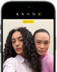 iPhone 18 Pro, musta, etupuoli, kaksi mallia poseeraa kameralle, kuvalla esitellään Center Stage ‑etukameraa