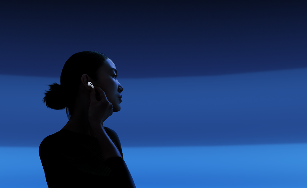 Henkilö pitelee AirPods 5 ‑kuulokkeiden vartta peukalonsa ja etusormensa välissä vaihtaakseen kuuntelutilaa
