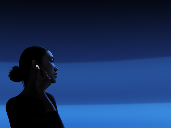 Henkilö pitelee AirPods 5 ‑kuulokkeiden vartta peukalonsa ja etusormensa välissä vaihtaakseen kuuntelutilaa