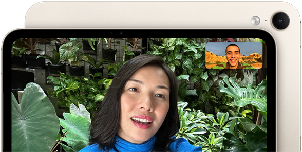 iPad mini edestä, esittelyssä vaakasuuntaisen 12 Mpix Center Stage ‑etukameran käyttöliittymä, henkilö puhuu videopuhelua vihreää kasvillisuutta vasten