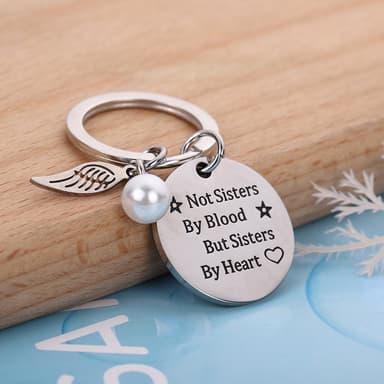 Avaimenperä siivellä ja tagilla tekstillä ""Sisters by Heart""