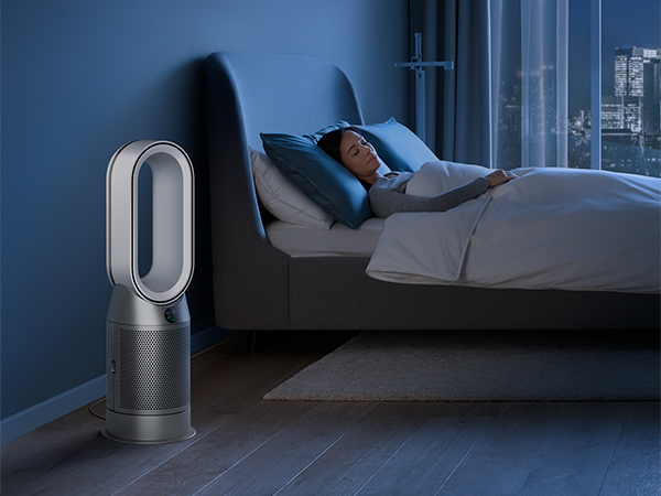 Nainen nukkumassa sängyssä ja Dyson Pure Hot&Cool -ilmanpuhdistin sängyn vieressä