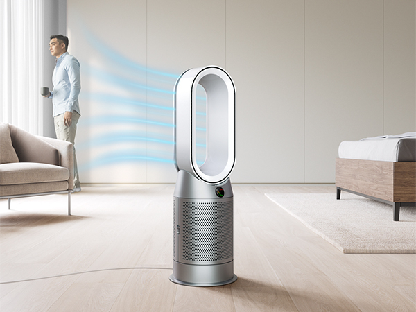 Mies seisoo ikkunan edessä ja Dyson Pure Hot&Cool -ilmanpuhdistin lattialla etualalla