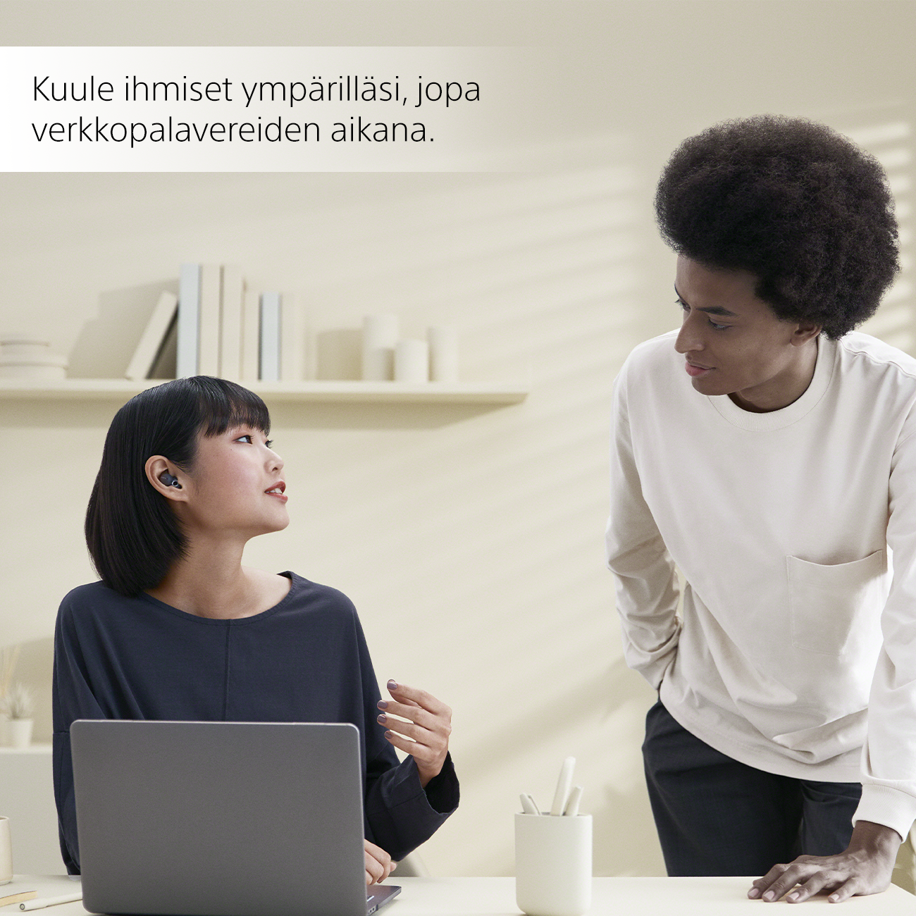 Nainen, jolla on Sony LinkBuds -kuulokkeet, puhuu miehen kanssa toimistossa