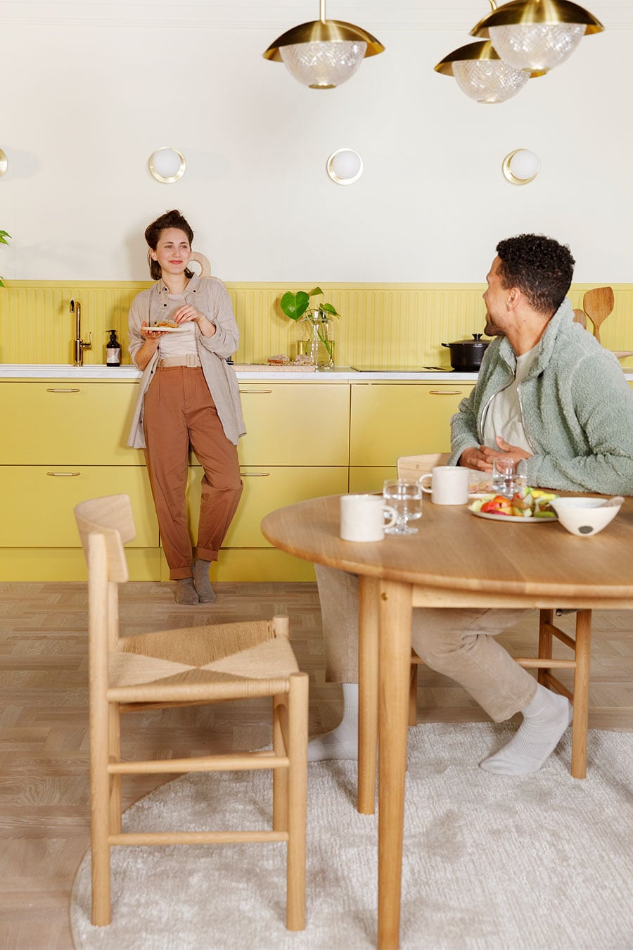 Keltainen Trend Mellow -keittiö ja nainen syömässä aamiaista miehen katsoessa vieressä