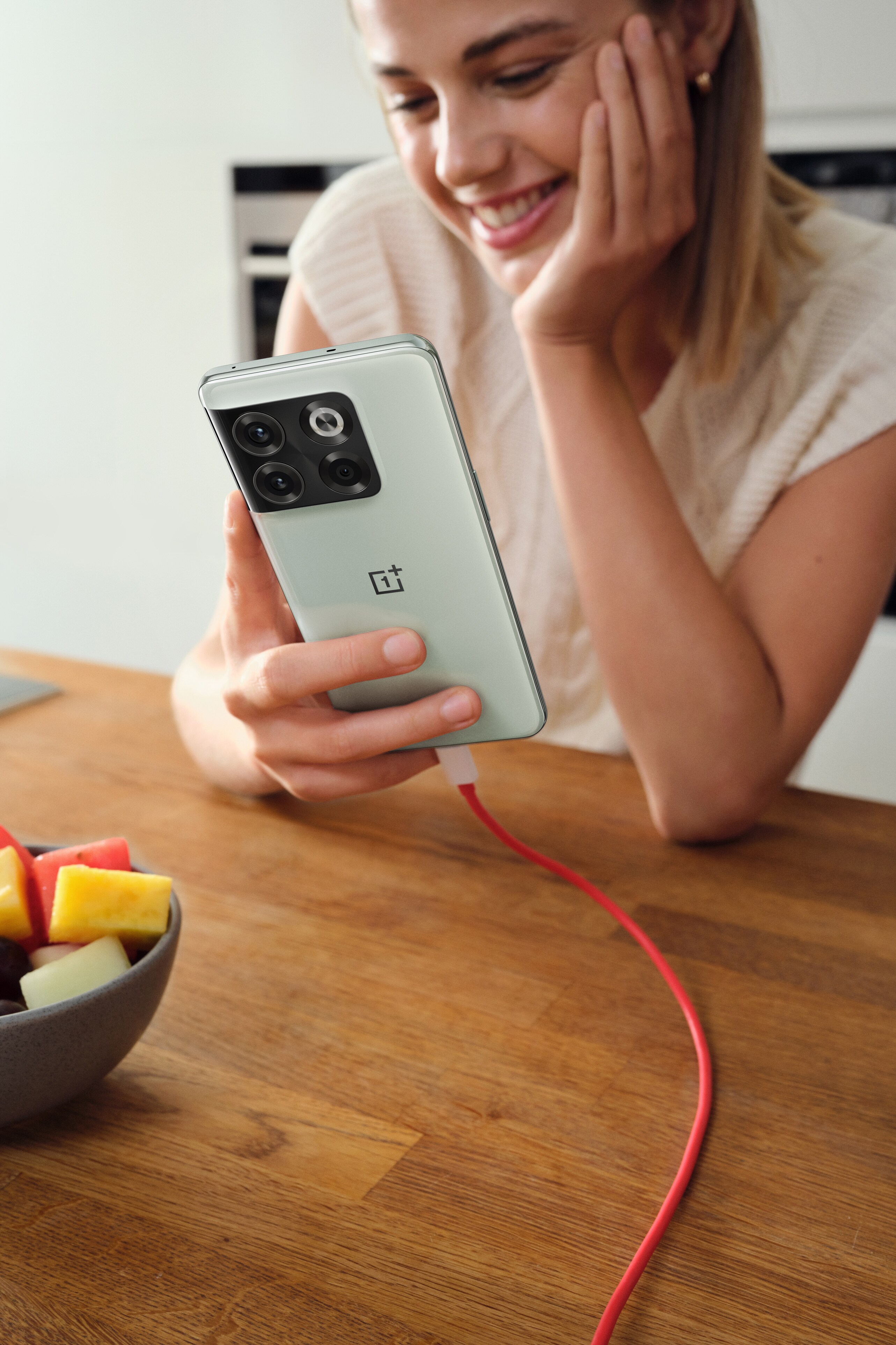 Hymyilevä tyttö lataa OnePlus 10T -älypuhelintaan
