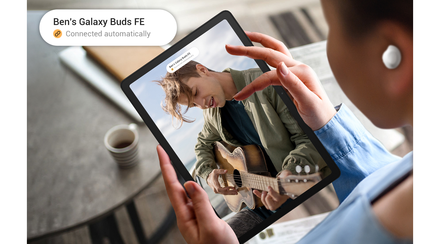 Henkilö käyttää Galaxy Tab A9 -tablettia Galaxy Buds FE -kuulokkeet korvissaan