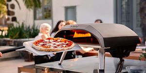 Pizza pizzauunin edessä ja ihmisiä taustalla