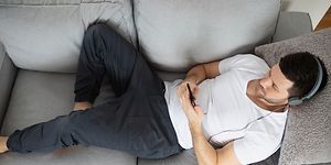 ME-Time - omaa aikaa - Kuulokkeet päässä oleva mies makaa sohvalla ja kuuntelee musiikkia