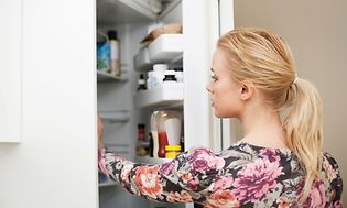 Nainen kurottamassa kättään jääkaapin sisään