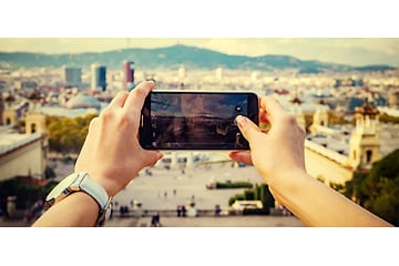 Nainen pitelee älypuhelinta kädessään ottaakseen kuvan kaupunkimaisemasta