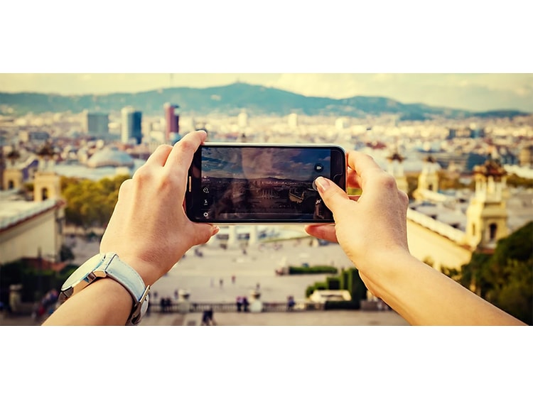 Nainen pitelee älypuhelinta kädessään ottaakseen kuvan kaupunkimaisemasta