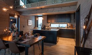 Puinen keittiö, jossa ruskeat pöydät ja mustat kodinkoneet