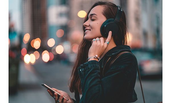 Nainen puhelimensa ja kuulokkeidensa kanssa