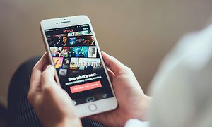 Henkilö suoratoistaa Netflixiä matkapuhelimestaan