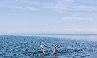 Nainen sukeltaa ja vain hänen jalkansa näkyvät vedenpinnan yläpuolella
