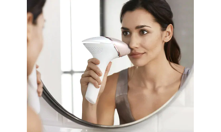 Nainen käyttää Philips Lumea Prestige -valoimpulssilaitetta kasvoissaan
