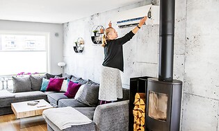 Sohvalla seisova nainen tarkistamassa lämpöpumpun suodatinta