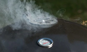 Hiiligrillin kansi, jonka tuuletusaukosta tulee savua