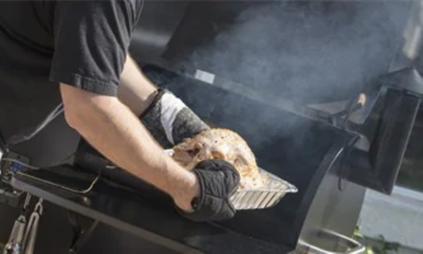 Mies savustaa lihaa grillillä