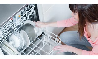 nainen laittamassa astioita astianpesukoneeseen