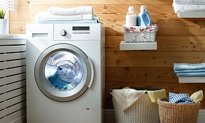 Pyykinpesukone käynnissä vieressään pyykkikorit pesutuvassa