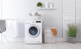 Valkoinen kuivaava pesukone valkoisessa pesutuvassa
