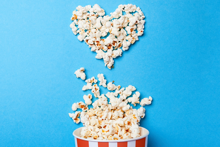 Popcornit aseteltu sydämen muotoon sinistä pöytää vasten