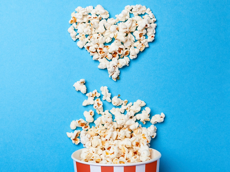 Popcornit aseteltu sydämen muotoon sinistä pöytää vasten
