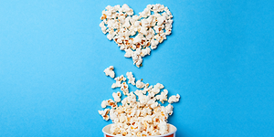 Popcornit aseteltu sydämen muotoon sinistä pöytää vasten
