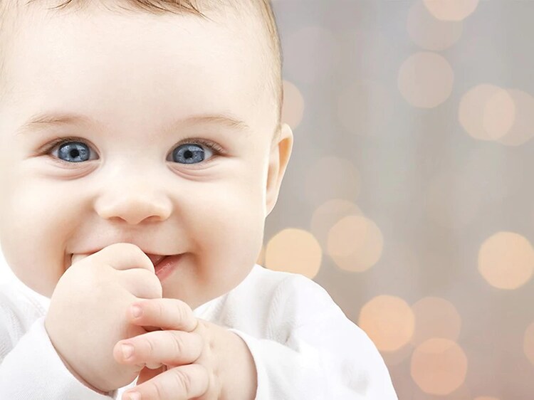 Hymyilevä vauva, jolla peukalo suussaan