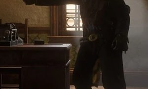 Red Dead Redemption 2 - mies pitelee asetta kädessään toimistossa