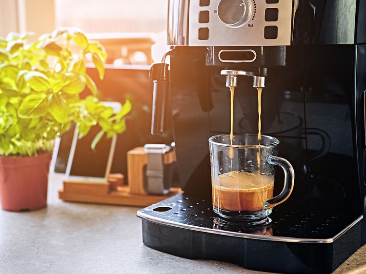 Kahvikone keittiön työtasolla josta valmistuu kahvia lasiseen kahvikuppiin